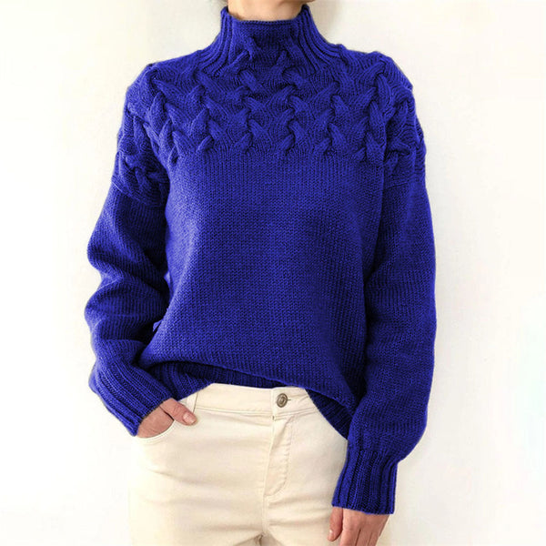 Blauwe gebreide trui met kabelpatroon, hoge hals en lange mouwen, gedragen door model. Perfect voor wintermode en casual outfits.