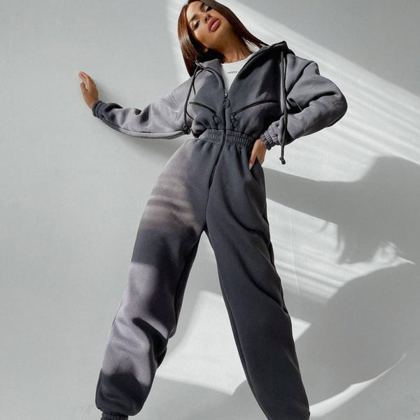 Vrouw poseert in grijs trainingspak, modieuze sportkleding, comfortabele loungewear, trendy outfit, casual stijl, moderne damesmode.