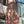 Vrouw in witte crop top en kleurrijke bohemian maxi-rok met paisley-patroon, staand op balkon met stadzicht. Zomermode, boho-chic stijl.