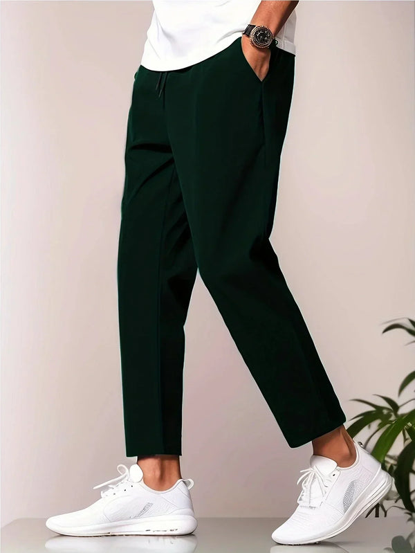Modieuze groene herenbroek, gecombineerd met witte sneakers en een casual wit T-shirt. Perfect voor een stijlvolle, eigentijdse look.