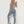 Vrouw in blauwe sportlegging en top, poseert tegen witte muur. Fitnesskleding, sportmode, actieve levensstijl.