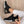 Zwarte sneakers met gouden details en witte zool, gedragen door persoon in witte broek op houten vloer. Stijlvolle damesmode, comfortabele schoenen.