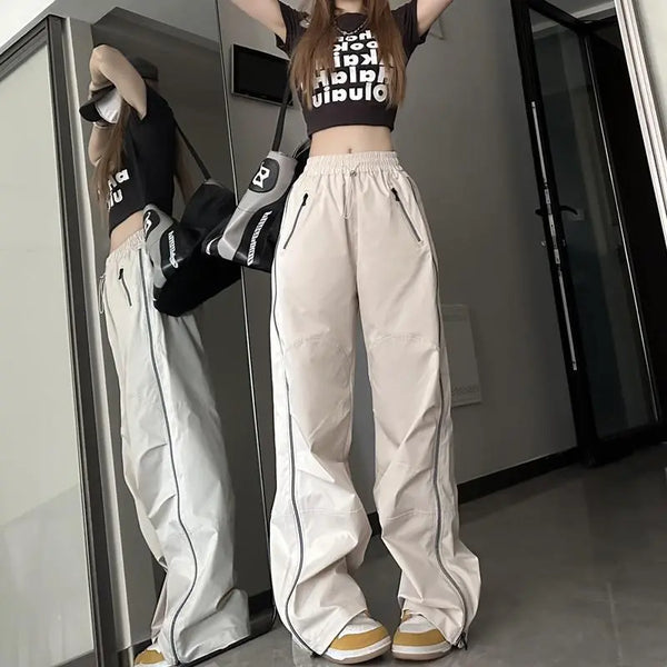 Vrouw in trendy sportieve outfit met beige wijde broek en zwart T-shirt, poseert voor spiegel. Streetwear mode, casual stijl, moderne kleding.
