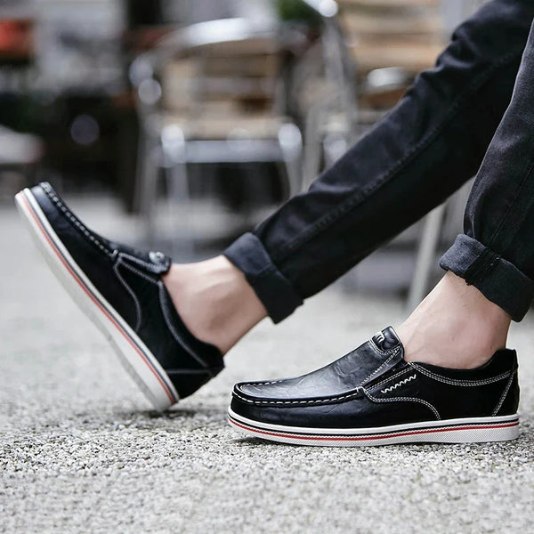 Zwarte leren loafers voor heren met witte en rode zool, gedragen met opgerolde jeans. Stijlvolle casual schoenen voor dagelijks gebruik.