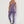 Vrouw in paarse sportkleding, bestaande uit een sportbeha en legging, poseert tegen een witte achtergrond. Fitnessmode, actieve kleding, sportoutfit.
