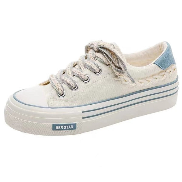 Witte canvas sneaker met dikke zool, gevlochten details en blauwe hiel. Casual damesmode, comfortabele schoenen, trendy streetwear.