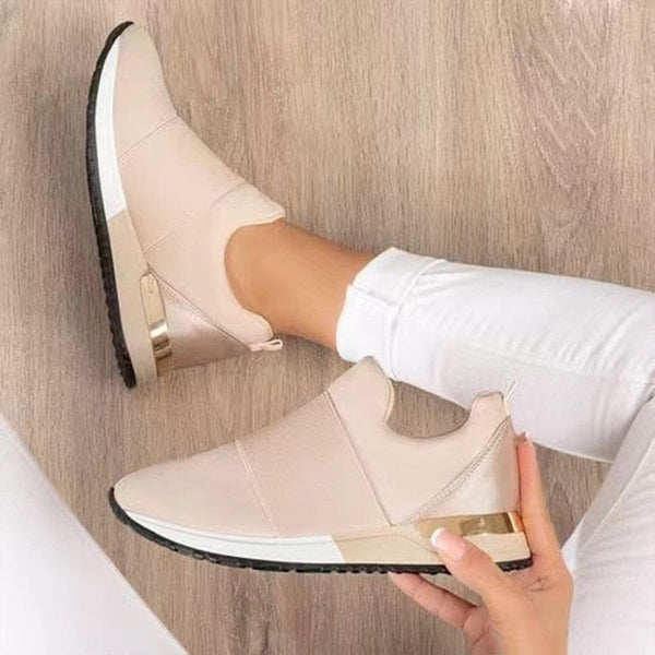 Beige dames sneakers met gouden details, comfortabele pasvorm, gedragen met witte broek op houten vloer. Trendy en stijlvol schoeisel.