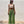 Vrouw in trendy groene gehaakte broek en beige crop top tegen witte muur. Mode, zomeroutfit, streetwear, casual stijl.