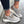 Grijze dames sneakers met dikke zool, perforaties en veters, gedragen met donkere jeans. Comfortabele en modieuze schoenen voor dagelijks gebruik.