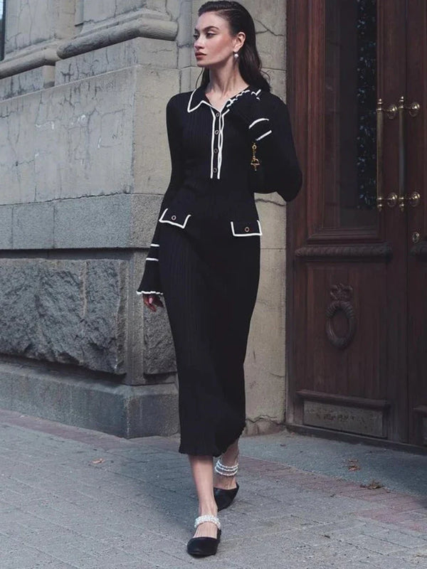 Vrouw in elegante zwarte outfit met witte accenten, loopt langs stenen gebouw. Modieuze kleding, stedelijke achtergrond, stijlvolle uitstraling.