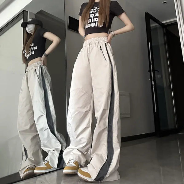 Vrouw in zwarte crop top en wijde beige broek met zwarte strepen, poseert voor spiegel. Trendy streetwear mode, casual outfit, moderne stijl.