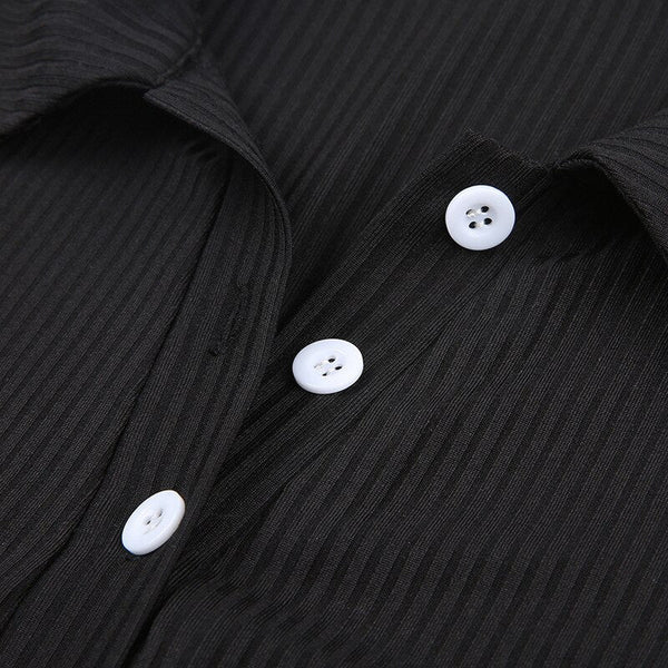 Zwarte geribbelde blouse met witte knopen, close-up. Modieuze dameskleding, elegant design, hoogwaardige stof. Perfect voor zakelijke outfits.