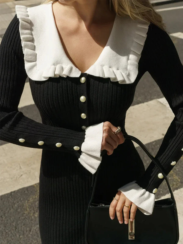 Vrouw in zwarte geribbelde jurk met witte kraag en knopen, houdt een zwarte handtas vast. Elegante mode, herfstkleding, straatstijl.