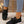 Zwarte dames sneakers met strik, gebreide stof, witte zool en bruine details, gedragen met blauwe jeans. Comfortabele en modieuze schoenen.