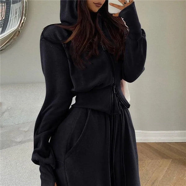 Vrouw in zwarte hoodie en joggingbroek, casual mode, comfortabele kleding, trendy loungewear, moderne woonkamer, houten vloer, spiegel.