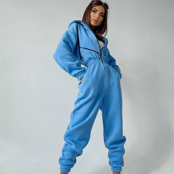 Vrouw in blauwe fleece jumpsuit met capuchon, comfortabele loungewear, casual mode, trendy dameskleding, winteroutfit, modieuze vrijetijdskleding.