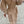 Vrouw in elegante beige wollen jas met brede kraag en pofmouwen, witte handtas en hakken. Modieuze herfst- of winteroutfit op straat.