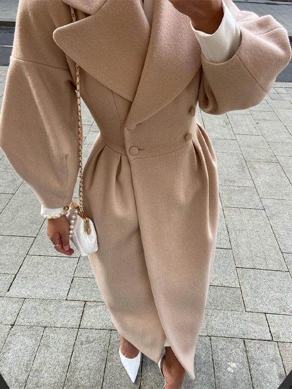 Vrouw in elegante beige wollen jas met brede kraag en pofmouwen, witte handtas en hakken. Modieuze herfst- of winteroutfit op straat.