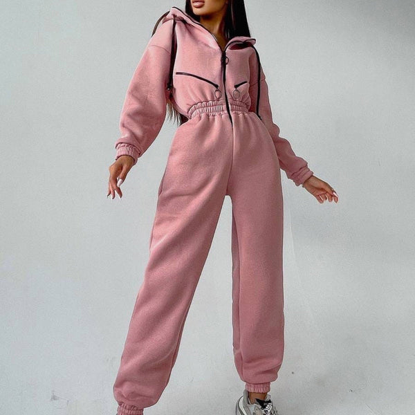 Vrouw in roze fleece jumpsuit met capuchon, elastische taille en sneakers. Modieuze dameskleding, comfortabele loungewear, trendy outfit.