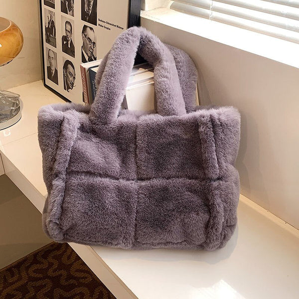 Grijze pluchen handtas op witte tafel bij raam, modieus en zacht, perfect voor winterse outfits. Luxe accessoire, trendy damesmode.