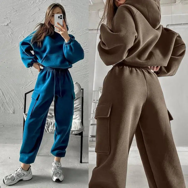 Twee vrouwen in comfortabele joggingpakken; links in blauw met sneakers, rechts in bruin met capuchon. Modieuze loungewear, casual stijl.