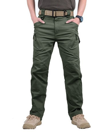 Groene tactische broek voor heren met meerdere zakken, riem en beige schoenen. Ideaal voor outdooractiviteiten en survival.