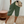Vrouw in casual outfit met groene linnen bermuda, witte sneakers en een beige schoudertas. Stijlvolle zomermode, comfortabele kleding.