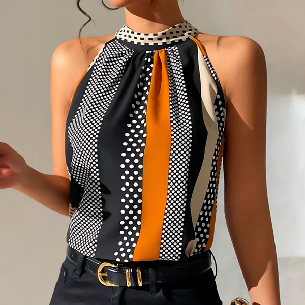 Vrouw in stijlvolle haltertop met zwart-wit stippen en oranje strepen, gecombineerd met zwarte broek en gouden riem. Modieuze dameskleding.
