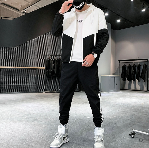 Moderne man in zwart-wit trainingspak met sneakers in minimalistische kledingwinkel. Stijlvolle sportkleding, urban fashion, herenkleding.