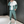 Man in groene en witte trainingspak met sneakers, staand in moderne kamer. Sportieve outfit, casual mode, herenkleding, streetwear stijl.