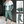 Groen-wit trainingspak voor heren, bestaande uit een jas met capuchon en joggingbroek. Sportieve outfit, ideaal voor casual en actieve gelegenheden.