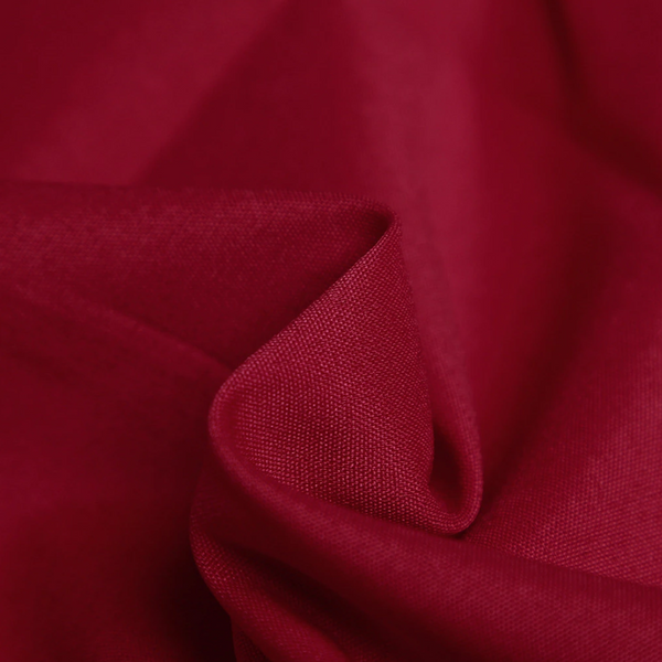 Rode katoenen stof close-up, textuur en plooien zichtbaar. Perfect voor mode, interieur en ambachtelijke projecten. Hoogwaardige textielmaterialen.