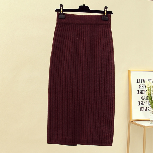 Bordeauxrode geribbelde midi-rok, hangend aan een hanger, tegen een neutrale achtergrond. Modieuze dameskleding, herfst-winter collectie.