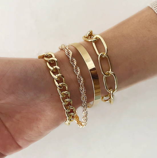 Gouden armbanden set op pols, inclusief schakelarmbanden en gedraaide ontwerpen, modieuze sieraden voor dames, trendy accessoires.