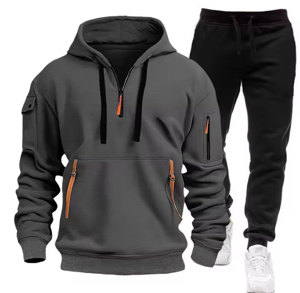 Grijze hoodie en zwarte joggingbroek set met oranje ritsen, comfortabele sportkleding voor heren, ideaal voor casual en sportieve activiteiten.