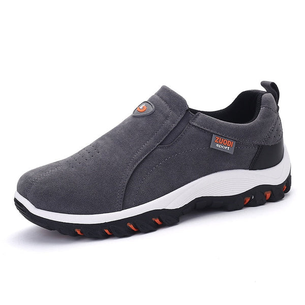 Grijze herensneaker met zwarte zool, oranje accenten en merklogo. Comfortabele sportieve schoen, ideaal voor dagelijks gebruik en wandelen.