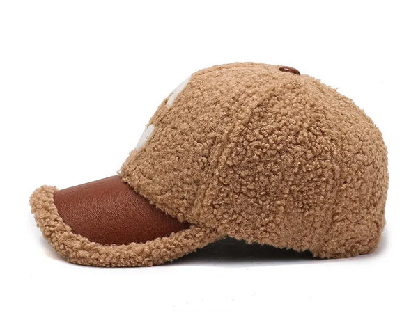 Bruine teddy cap met gebreide textuur en leren klep, zijaanzicht. Modieuze winteraccessoire, unisex design, warme en comfortabele pet.