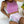 Vrouw in roze sporttop en hoge taille bikini met tropisch bladpatroon, liggend op witte kussens naast een ananas. Zomerse strandmode.