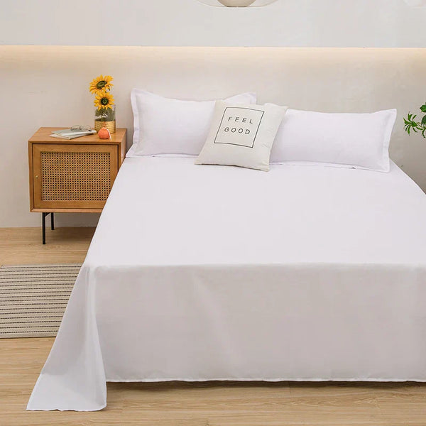 Wit beddengoed op een tweepersoonsbed met kussen "Feel Good", naast houten nachtkastje met zonnebloemen en sinaasappel, moderne slaapkamerinrichting.