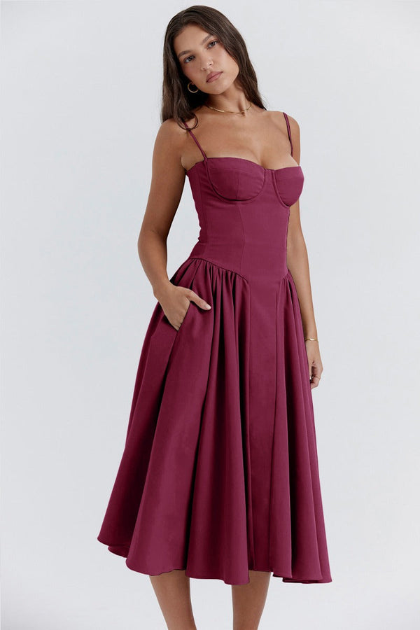 Vrouw in elegante bordeauxrode jurk met spaghettibandjes en wijde rok, perfect voor avondkleding. Modieuze damesmode, stijlvolle jurk.