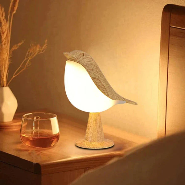 Houten vogel tafellamp op nachtkastje, sfeerverlichting naast glas whisky, modern interieur, Scandinavisch design, warme gloed, slaapkamerdecor.