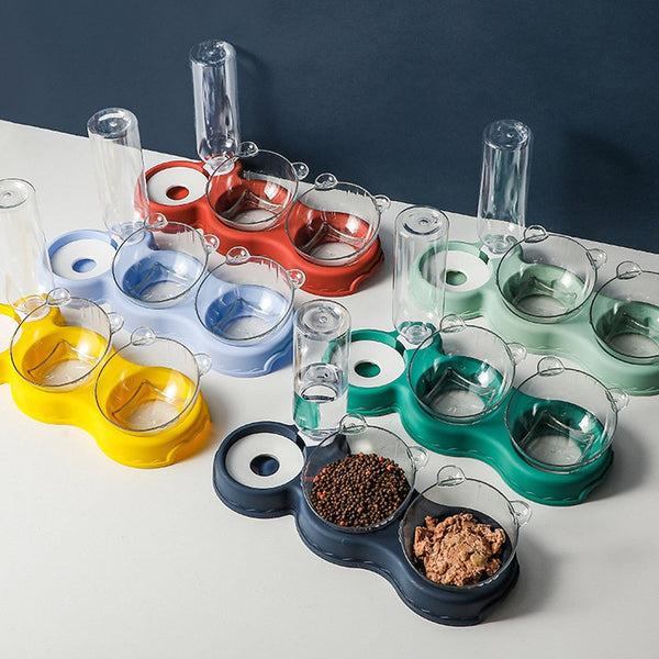 Verschillende kleurrijke huisdier voer- en waterbakken met transparante waterdispensers, ideaal voor honden en katten, op een witte en grijze achtergrond.