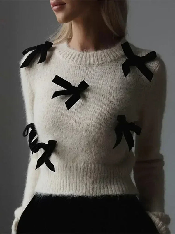Vrouw draagt witte wollen trui met zwarte strikjes, modieuze dameskleding, herfst-winter stijl, elegant en trendy design, comfortabele pasvorm.