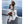 Vrouw in witte zomerjurk en hoed poseert op terras met zeezicht, Santorini. Zonnebril, strandmode, vakantie, Griekenland, stijlvolle outfit.