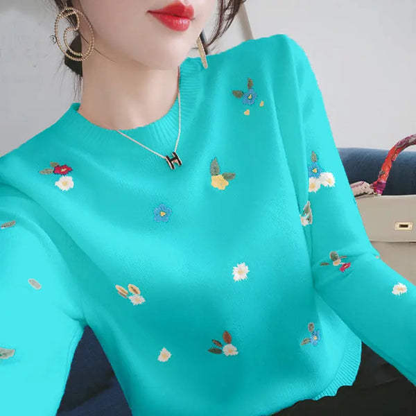 Vrouw in turquoise trui met geborduurde bloemen, gouden oorbellen en rode lippenstift. Modieuze dameskleding, casual stijl.