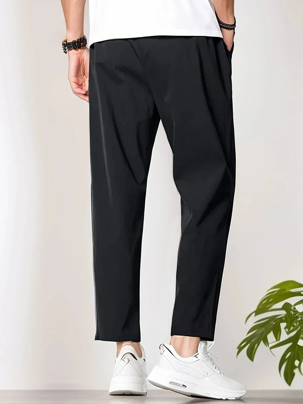 Zwarte herenbroek, casual stijl, gedragen met witte sneakers. Comfortabele pasvorm, geschikt voor dagelijks gebruik. Trendy herenkleding.
