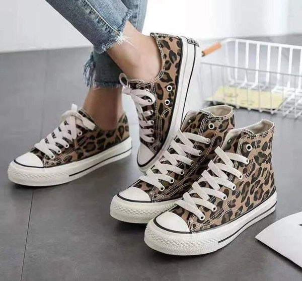 Luipaardprint sneakers met witte veters en rubberen zolen, gedragen door persoon in blauwe jeans. Modieuze casual schoenen voor dames.