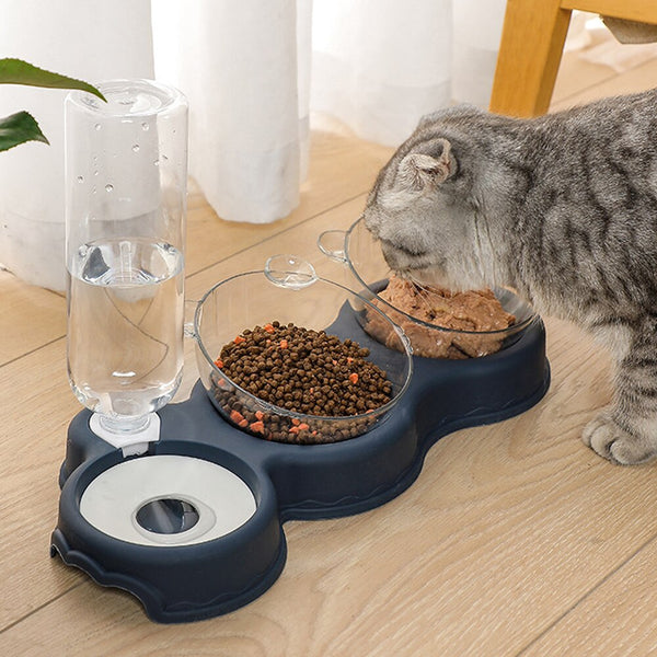 Grijze kat eet uit een dubbel voerbak met waterdispenser, gevuld met droog- en natvoer, op houten vloer. Ideaal voor huisdierverzorging.