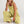 Vrouw in olijfgroene jumpsuit, zittend op witte achtergrond. Modieuze dameskleding, casual stijl, comfortabele pasvorm, trendy outfit.