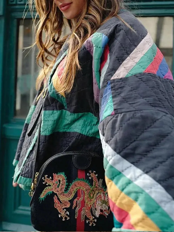 Vrouw in kleurrijke gewatteerde jas met gestreept patroon, draagt een zwarte tas met geborduurde draak. Modieuze streetwear outfit.